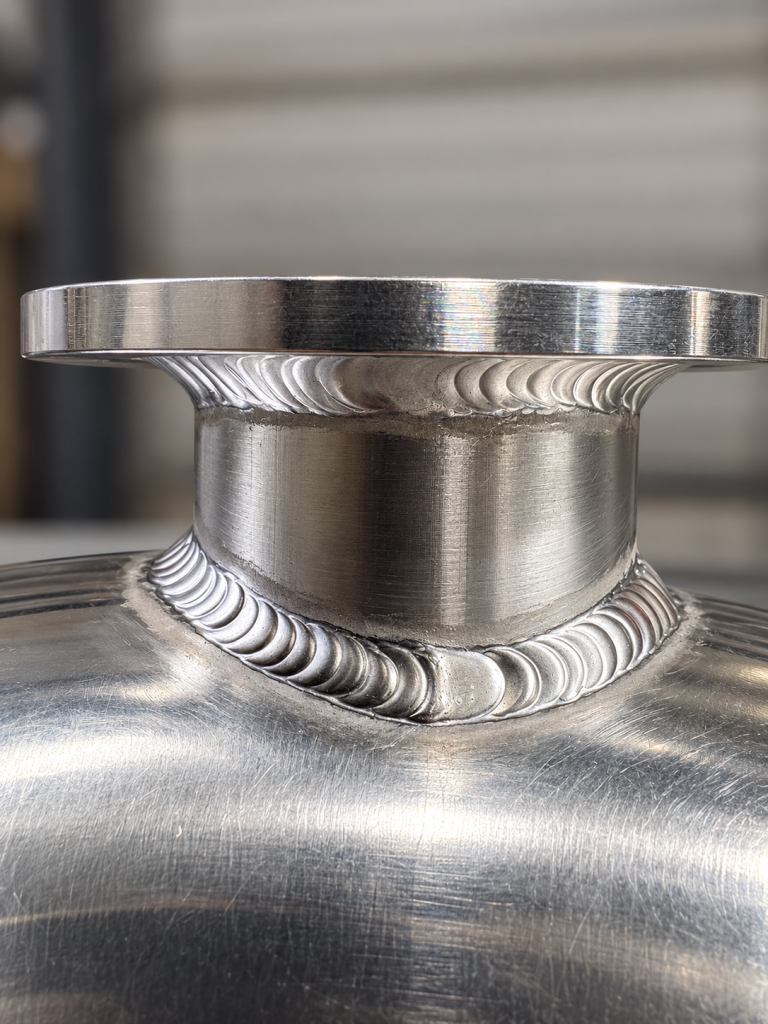 Close-up of welds around a metal neck and circular flange.